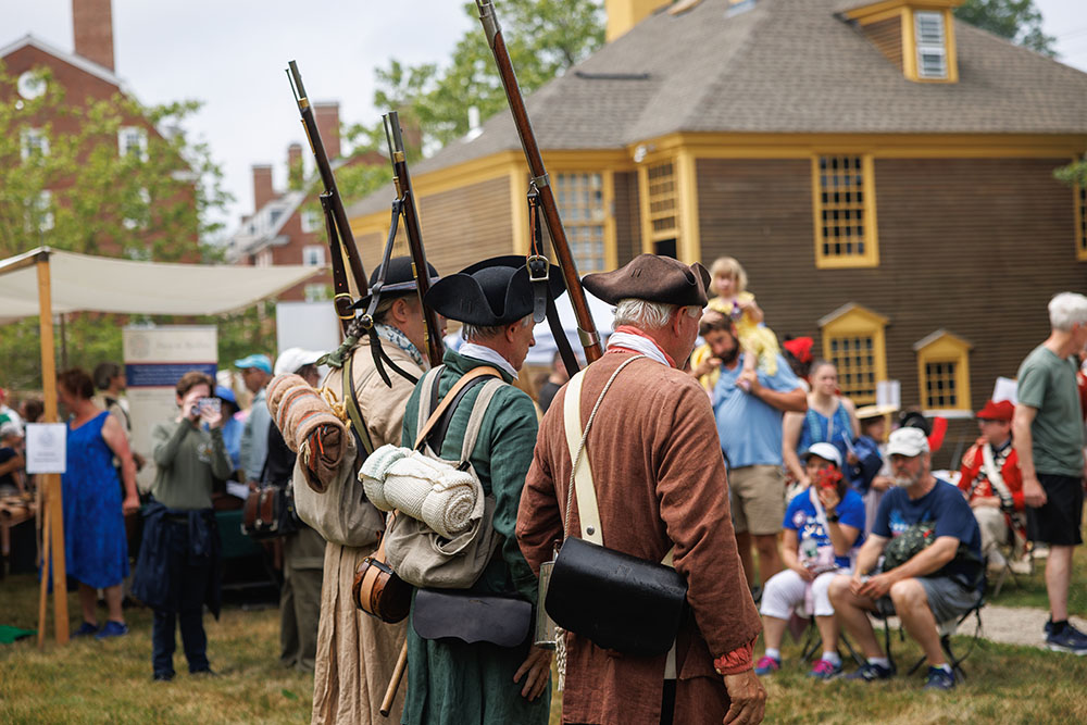 3 men dressed in period costumes at a historic event