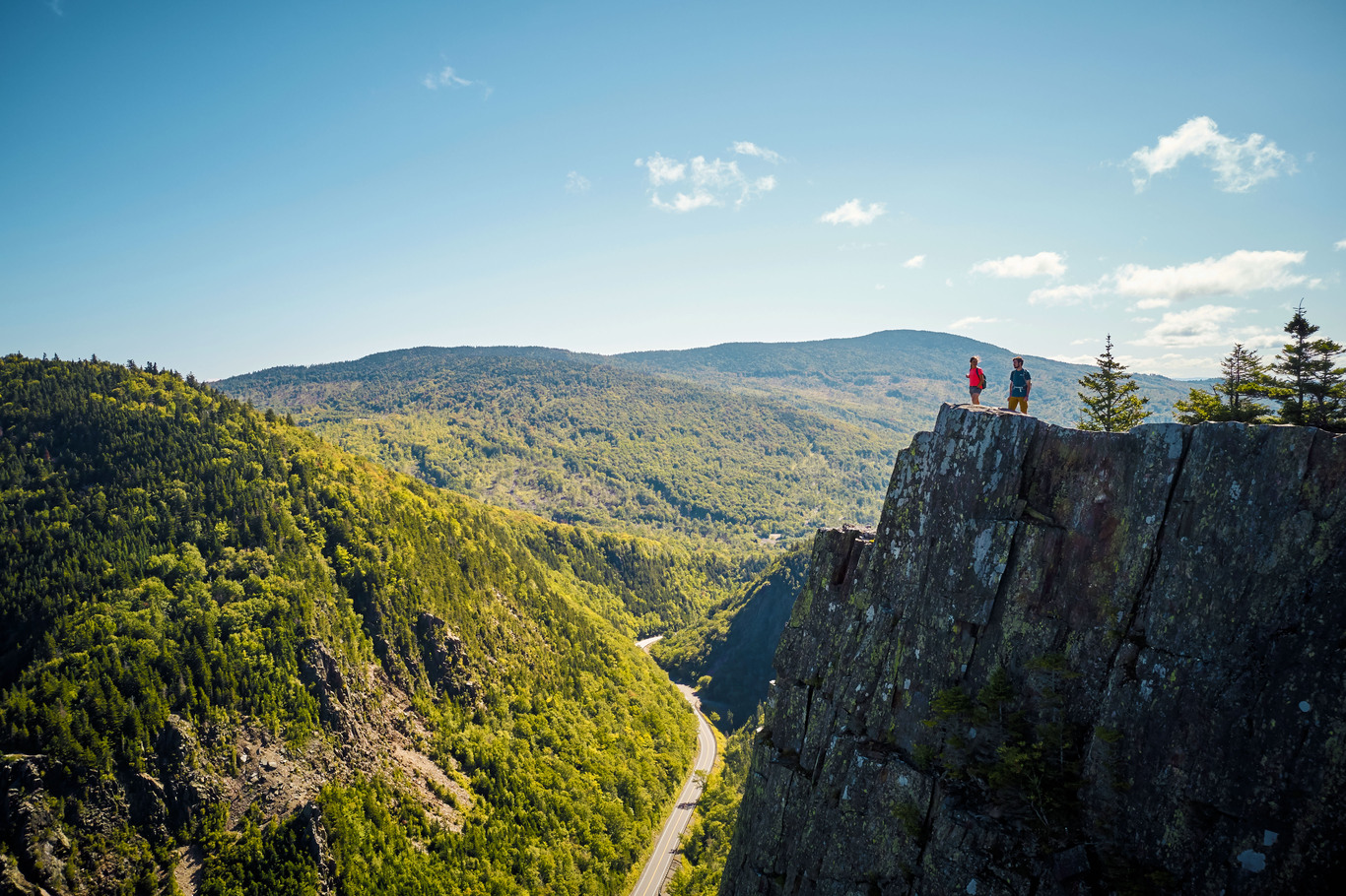 people standing at the top of the mountain overlooking a valley