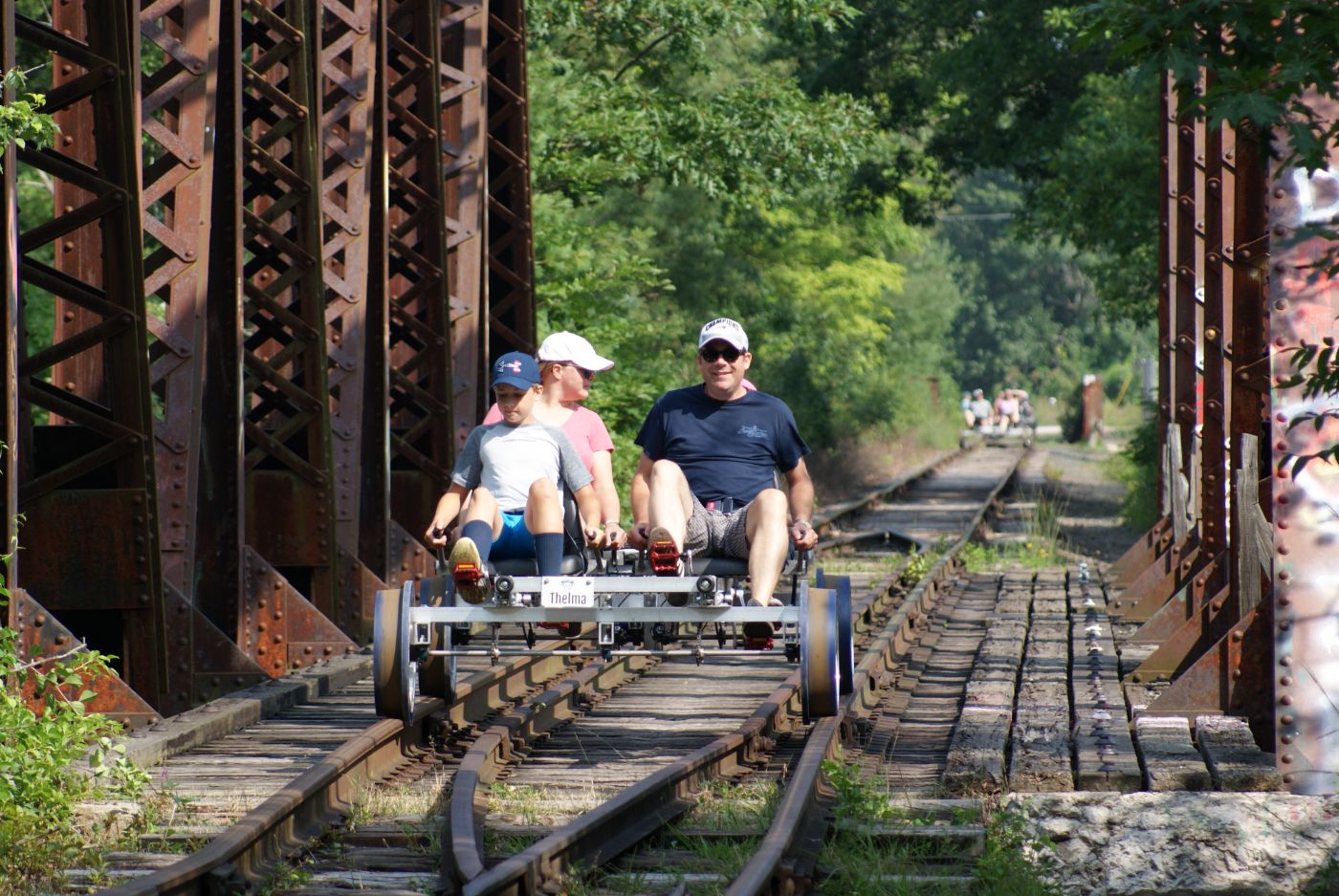 Family of 4 pedaling across our Thru Riveted Warren Truss Bridge that crosses over where the Contoocook and Merrimack rivers meet.