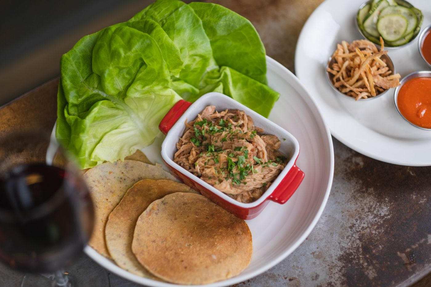 Johnny Cake Community with brown sugared pork shoulder, house sauces, crispy onion, pickled cucumbers, and cornmeal pancake