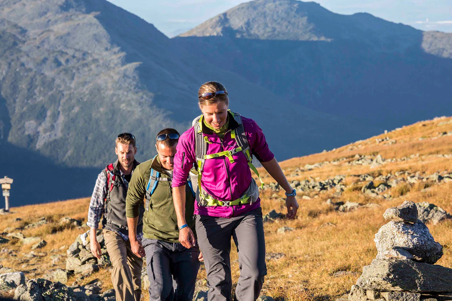 Hikers hiking up a mountain with another mountain in the background